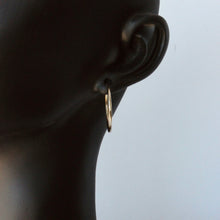 Load image into Gallery viewer, 14k gold flexible tube hoops on mannequin against white background