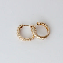 Load image into Gallery viewer, A pair of small gold hoop earrings with a textured, beaded outer edge, displayed on a plain light gray background. Talayee Fine Jewelry's Atousa Huggie Hoop Earrings.