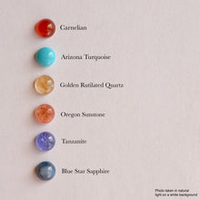 Load image into Gallery viewer, Six polished gemstone beads arranged vertically on a light beige background, each labeled with its name: Carnelian, Arizona Turquoise, Golden Rutilated Quartz, Oregon Sunstone, Tanzanite, and Blue Star Sapphire.