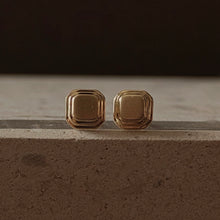 Load image into Gallery viewer, Pair of gold square earrings on a dark surface