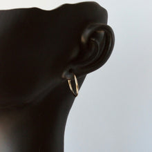 Load image into Gallery viewer, Gold hoop earring on a black mannequin ear against a light gray background
