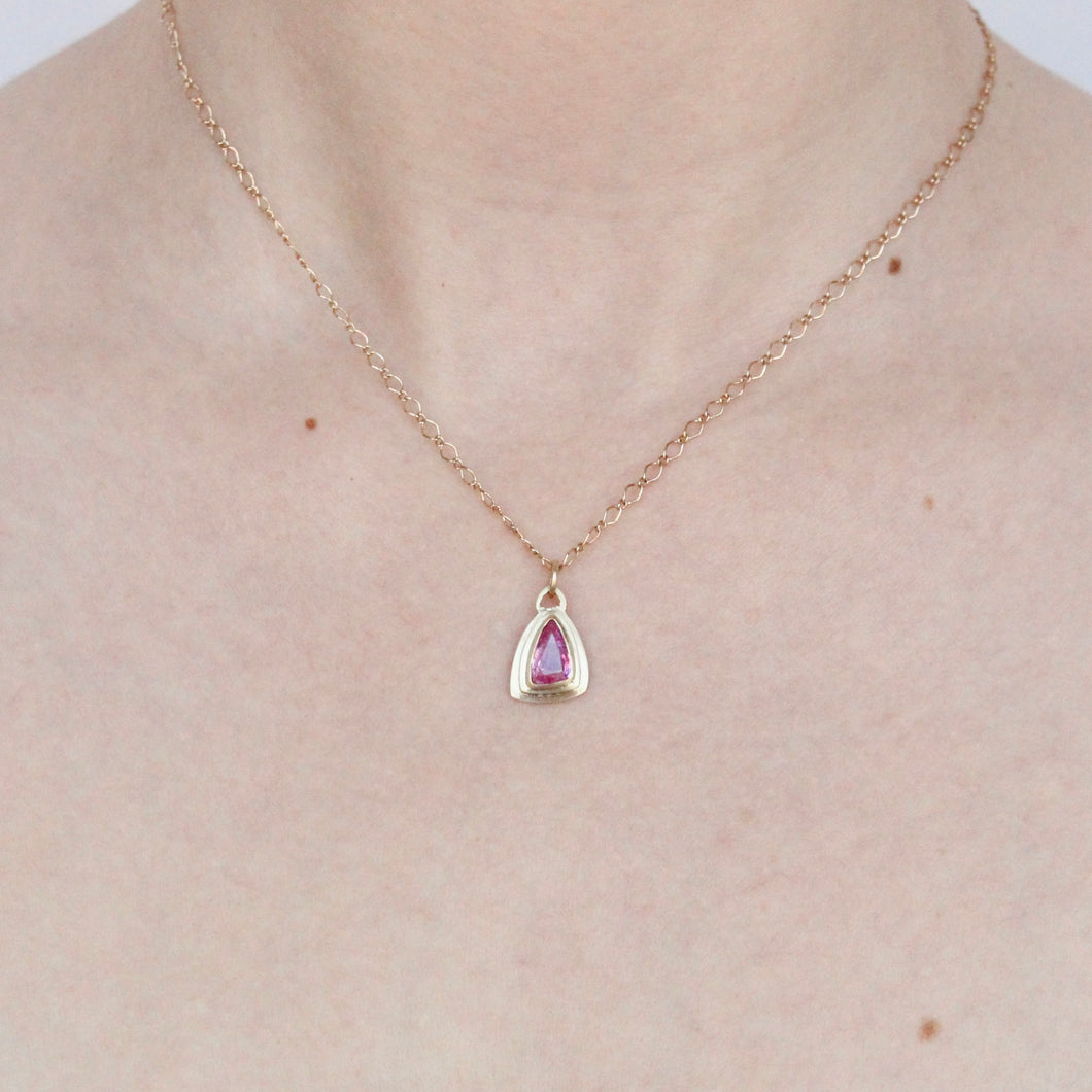 talayee fine jewelry's persepolis pendant featuring a hot pink sapphire set in 14k gold on figure