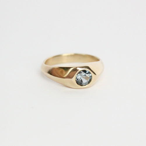 14k yellow gold ring with a gray flush set spinel on a light gray background