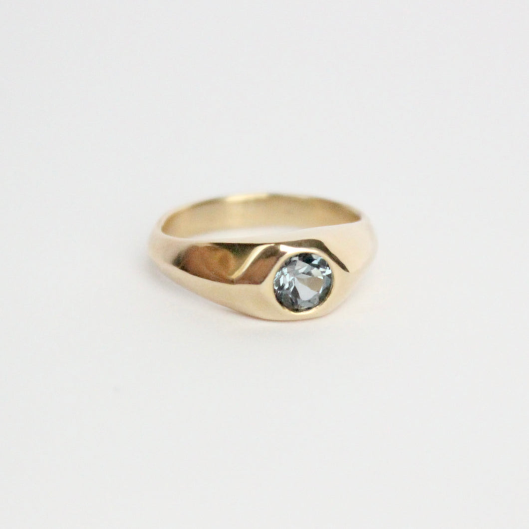 14k yellow gold ring with a gray flush set spinel on a light gray background