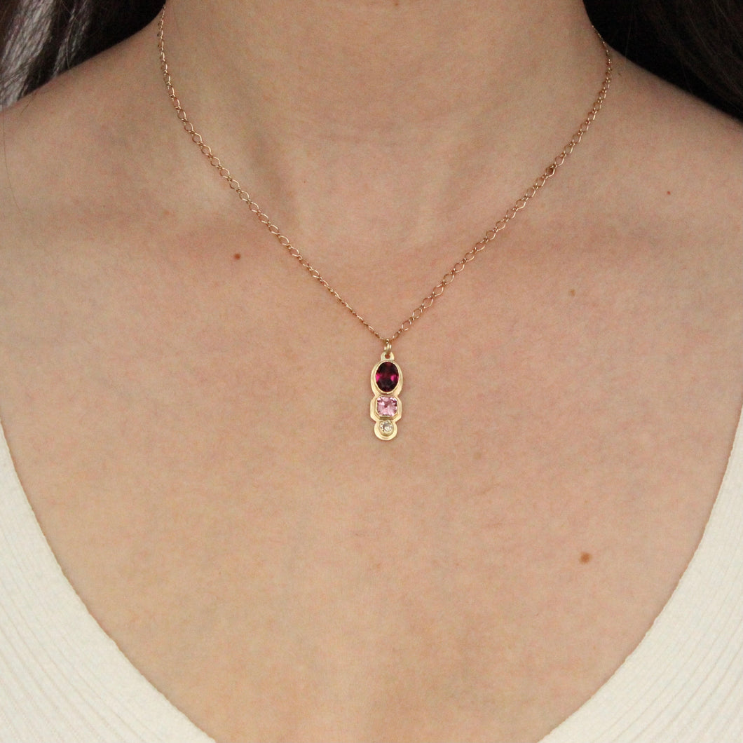 Talayee Fine Jewelry's latest iteration of the Persepolis Pendant design featuring three gemstones, a rhodolite garnet, champagne diamond, and pink spinel. Handmade in San Francisco in 14k solid gold.