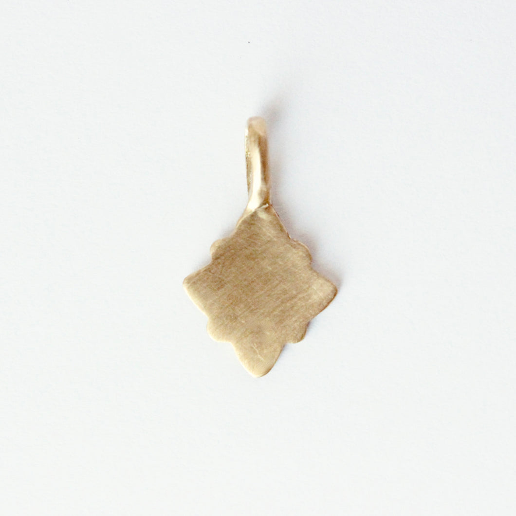 14k gold charm in a geometric shape on a light gray background.