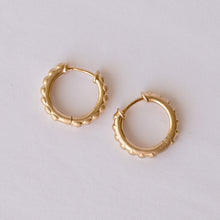 Load image into Gallery viewer, A pair of small gold hoop earrings with a textured, scalloped outer edge, displayed on a clean white background. Talayee Fine Jewelry's Atousa Huggie Hoop Earrings.
