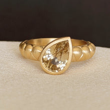 Load image into Gallery viewer, Talayee Fine Jewelry's Atousa Bezel Ring featuring a pear shaped golden zircon bezel set in 18k gold on the signature textured band shown sitting on white silk against a black background
