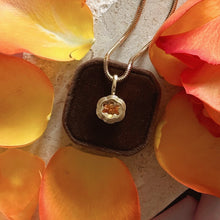 Load image into Gallery viewer, Talayee Fine Jewelry&#39;s Bloom Pendant. 18k Yellow Gold pendant with an orange garnet in a flower setting shown on a brown velvet cushion surrounded by orange petals.
