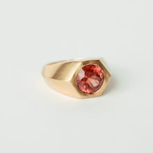 Load image into Gallery viewer, A gold signet ring featuring a faceted, round malaya garnet, photographed on a clean, light gray background.
